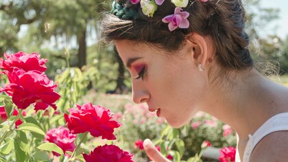A woman activating her sense of smell by sniffing a flower