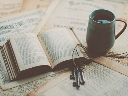 Taza de té junto a un libro y unas llaves antiguas