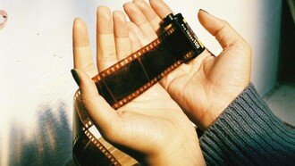 Mani attente e delicate avvolgono la pellicola cinematografica, come a proteggere storie, ricordi e sogni racchiusi in ogni fotogramma