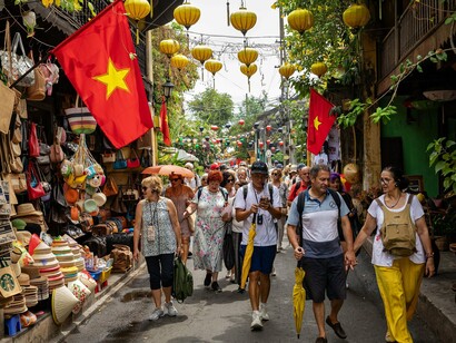 Visitors walking beneath Vietnamese flags and lanterns in a historic quarter, symbolising the connection between tourism and national identity