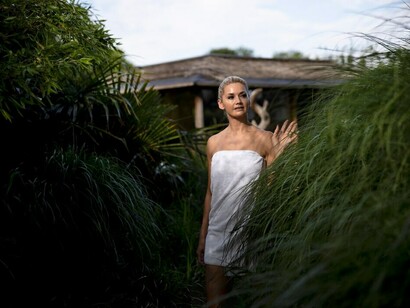 A woman enjoying a peaceful moment at an outdoor spa in an eco-conscious boutique hotel, highlighting sustainable hospitality and green design principles