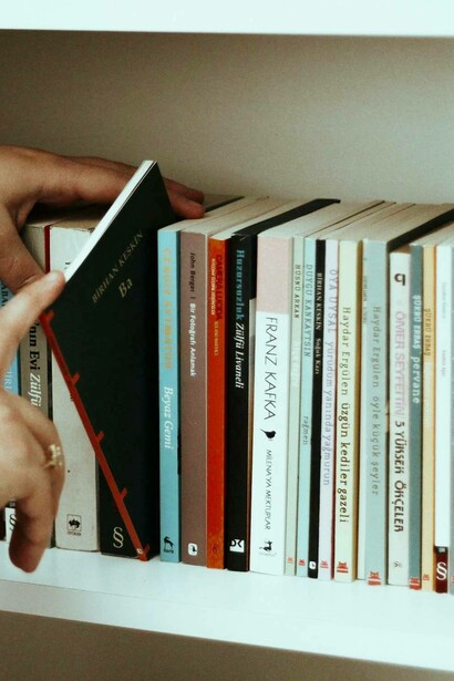 Una persona sceglie un piccolo libro nero dallo scaffale di una libreria