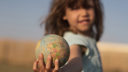 Niña sosteniendo un globo terráqueo