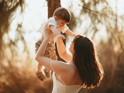 A loving mom lifting her child with delight, symbolising the nurturing relationships that become a child's first understanding of the world