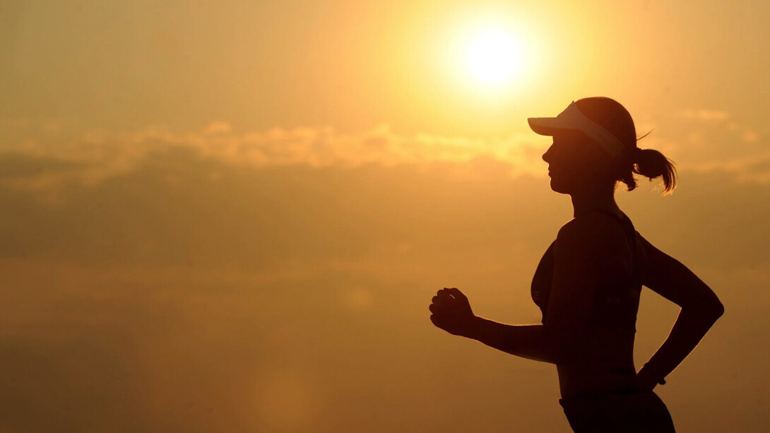 Ragazza motivata corre con il sole alle spalle che tramonta