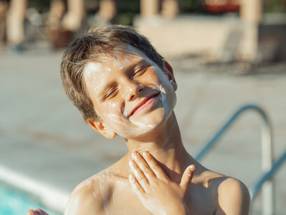 It is essential when going into the sun to use sunscreen, as a boy puts it all over his face and body