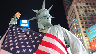 The Statue of Liberty draped in the American flag, wearing sunglasses
