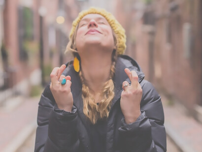 A hopeful woman holding her hands in a wish-making gesture on the road
