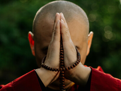 A monk raises his hands to his head to pray