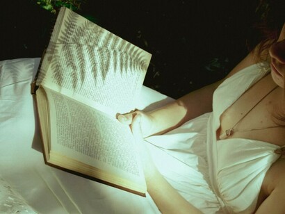 A person is reading a book while surrounded by nature