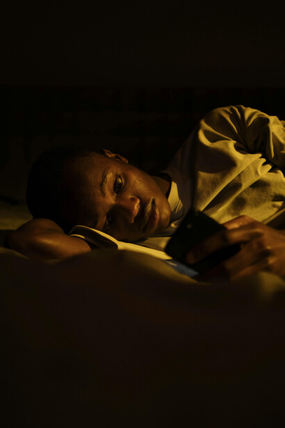 An anxious person scrolling through their phone late at night, unable to disconnect