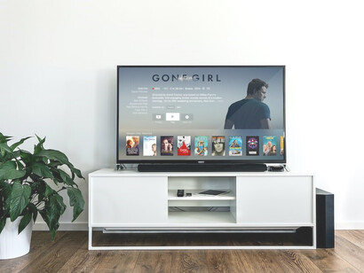 A flat-screen TV displaying 'Gone Girl' against a backdrop of white walls