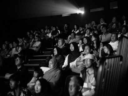 Dans l’obscurité d’une salle, les spectateurs vivent ensemble les défilés, transformant la Fashion Week en expérience collective