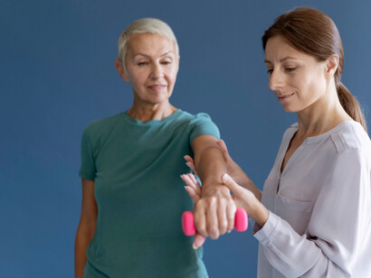 A woman receives guidance for a resistance exercise, light dumbbells help preserve muscle mass and metabolic boost 