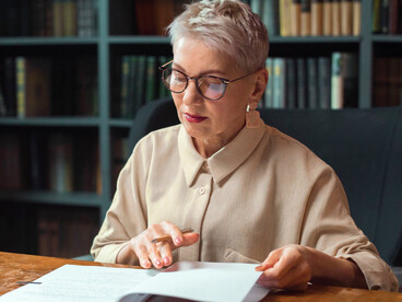 A linguist studying historical records with focused attention, symbolising the connection between ancient traditions and modern Greek identity