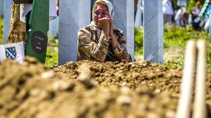 Una mujer llora ante una tumba en el memorial y cementerio de Srebrenica