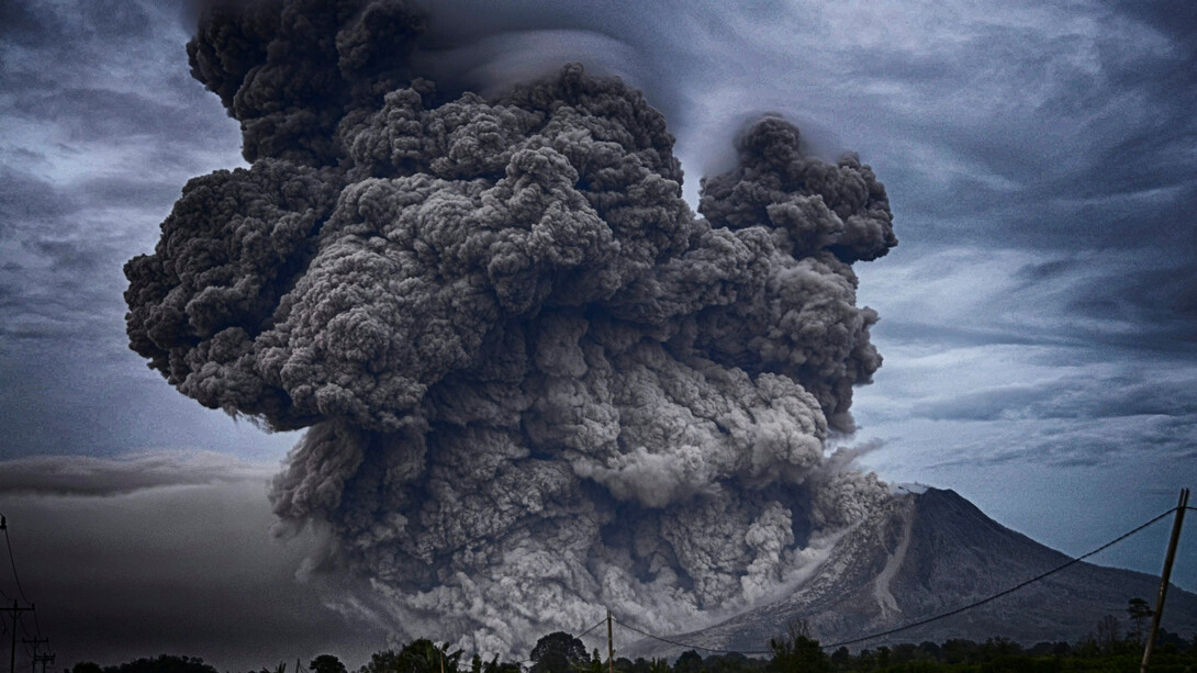 A powerful eruption at Mount Sinabung, Indonesia, with a massive ash cloud rising into the sky during the day