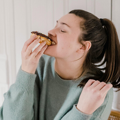 Mulher comendo donut. Atente-se às porções: o tamanho das porções é importante