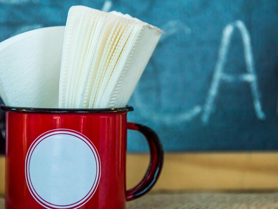 Guardanapos guardados numa caneca vermelha, à espera de uso como tantas presenças silenciosas que ocupam espaço na rotina sem realmente cumprir a função