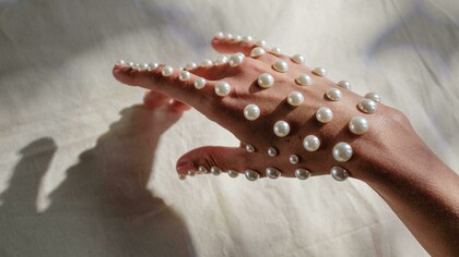 Pérolas usadas como adorno em mão. Este artigo explora a versatilidade das pérolas na moda atual e como elas estão a ser reinterpretadas por designers e estilistas