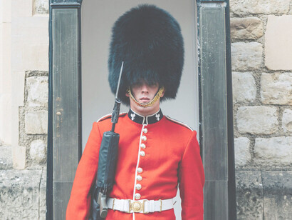 A British Royal Guard is standing attentively outside the Buckingham Palace