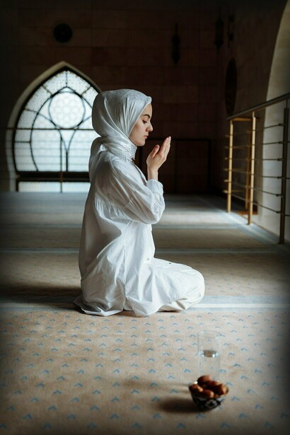 Muslim woman raising her hands in prayer in mosque