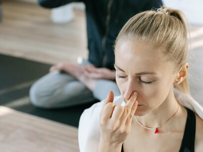 A woman practicing alternate nostril breathing, a deep breathing technique that helps balance the left and right hemispheres of the brain, calm the nervous system, and improve focus and concentration