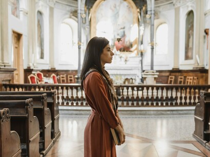 A woman standing quietly in the sanctuary with a Bible in hand, reflecting a heart seeking to remain steadfast in faith
