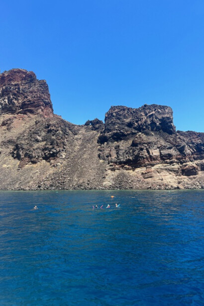 Seaside serenity: swimmers in the waters of Santorini, Greece