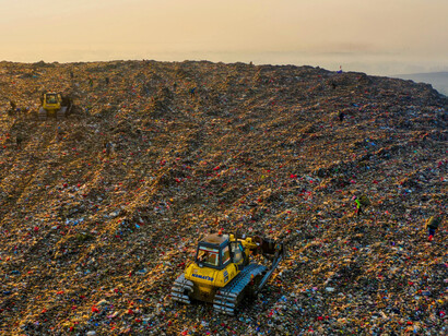 A sprawling landfill layered with discarded debris, representing the environmental cost of unchecked consumption