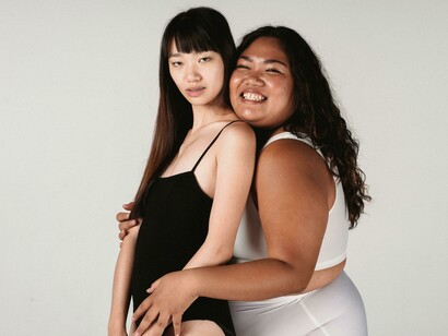Asian same-sex couple hugging warmly in front of a gray background
