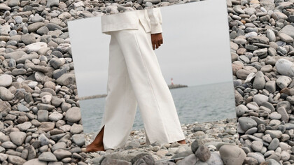 Barefoot on the rocks, a model steps into herself grounded in reflection and free to feel