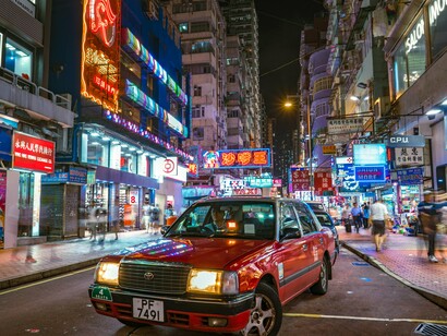 A bustling Hong Kong street illuminated by neon signs and city traffic, representing the vibrant nightlife and energy of the metropolis