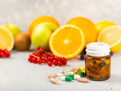 An assortment of food supplements and vitamins paired with fresh fruits, emphasizing balanced nutrition and wellness