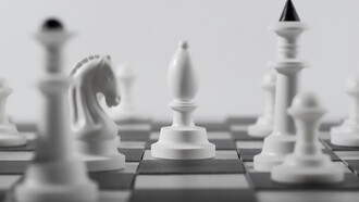 A monochrome set of white chess pieces arranged on a chessboard