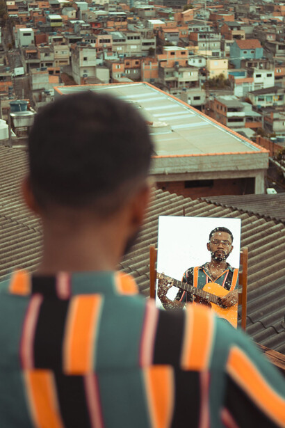 Jovem músico toca violão em cima da laje de sua casa localizada no Complexo do Morro do Alemão, no Rio de Janeiro, Brasil