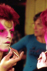 David Bowie no camarim maquiando-se como Ziggy