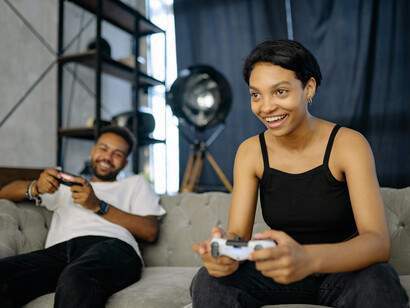 A couple smiling and having fun while playing a console game side by side