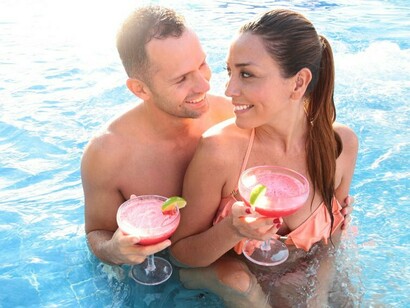 Una pareja tomando un cóctel en la piscina de un hotel