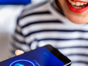 A close-up of her hand holding the device as a cheerful woman smiles, while an AI assistant analyzes visual input and delivers insights, supporting her in organizing and planning within a seamless modern lifestyle