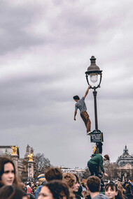 A man climbing a light tower during protests in Paris, France