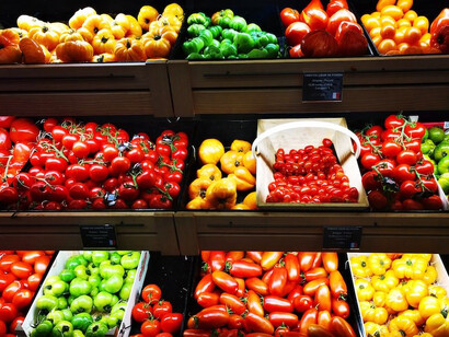 Assorted fruits are elegantly displayed on shelves at La Grande Epicerie de Paris, France, showcasing a vibrant variety of tomatoes in different colors and shapes