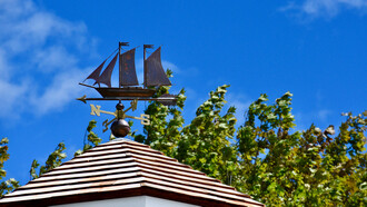 Veleta con forma de barco encima del techo de una cabaña