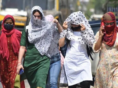 Amid rising temperatures, people in India cover their faces and heads as they navigate the streets under extreme hea