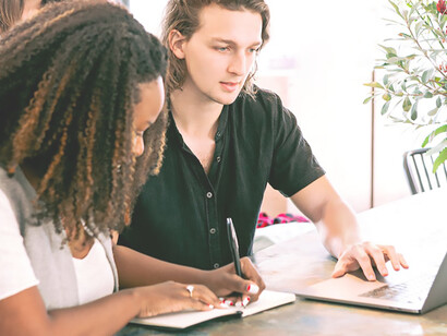 A harmonious scene: a man engrossed in laptop tasks while a woman attentively takes notes, epitomizing collaborative productivity in motion