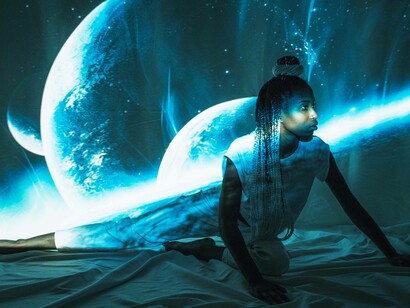 Woman poses by a model of space