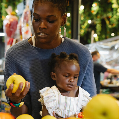 Mãe segura alimento natural, sem rótulos ou código de barras para alimentar a filha
