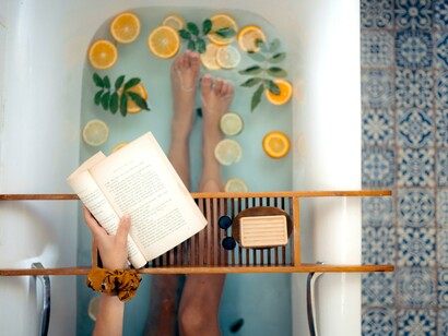 Mulher lê livro enquanto toma banho relaxante