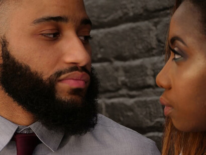 A woman stands beside a man in a distinguished grey shirt and necktie
