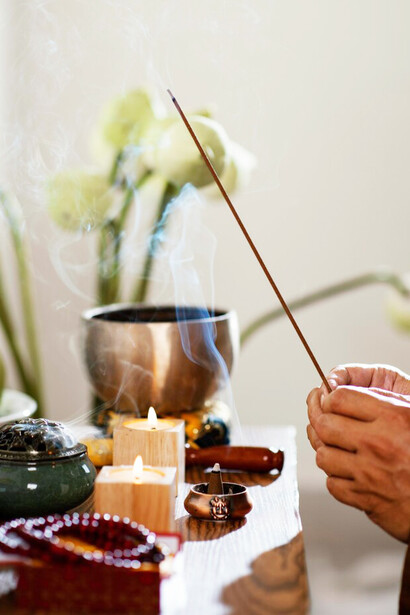 A man lighting an incense stick is engaging in meditation and healing, utilizing stress relief techniques to promote relaxation and mental clarity